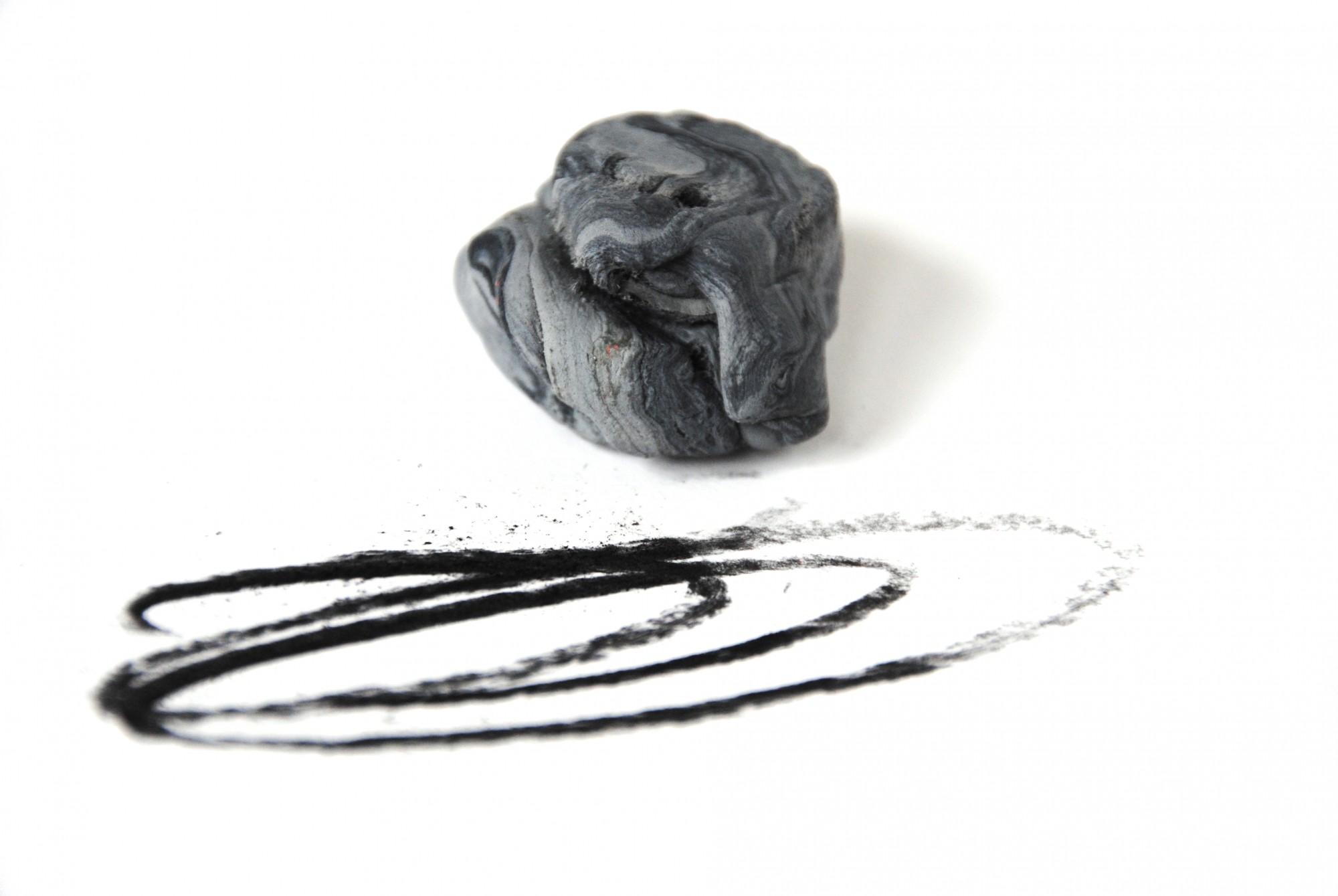 A piece of putty being used to absorb charcoal markings on paper.